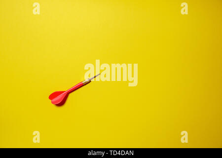 Single red arrow dart isolated on yellow background Stock Photo