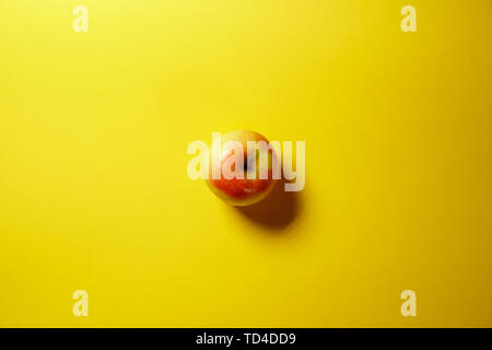 Single red apple isolated on yellow background Stock Photo