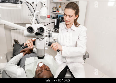 Female dentist advanced user, dental tools. Setup microscope for examining his patients teeth. in dental clinic office. Medicine, dentistry and health Stock Photo