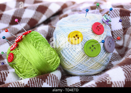 Buttons of different colors, and the two tangle thread on checked plaid Stock Photo