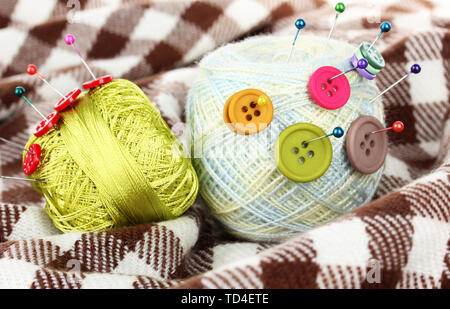 Buttons of different colors, and the two tangle thread on checked plaid Stock Photo