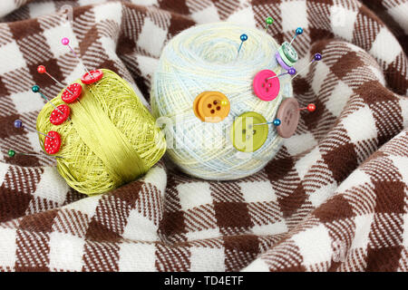 Buttons of different colors, and the two tangle thread on checked plaid Stock Photo