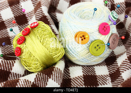 Buttons of different colors, and the two tangle thread on checked plaid Stock Photo