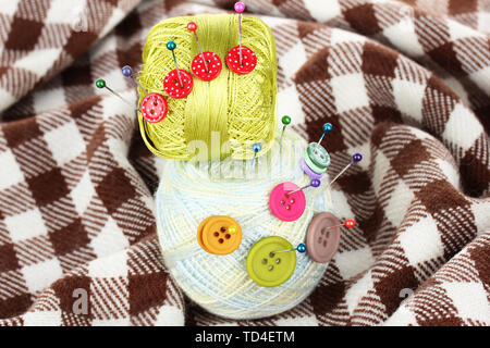 Buttons of different colors, and the two tangle thread on checked plaid Stock Photo