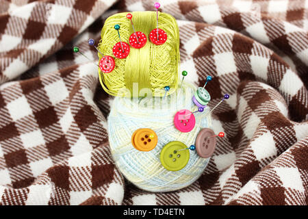 Buttons of different colors, and the two tangle thread on checked plaid Stock Photo