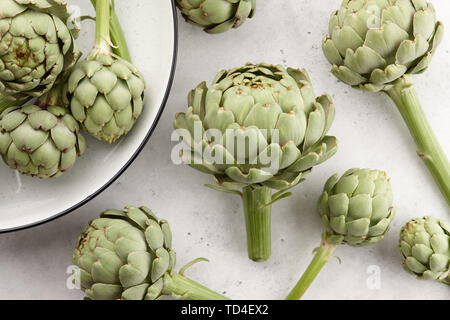 Fresh green artichokes on white stone background Stock Photo