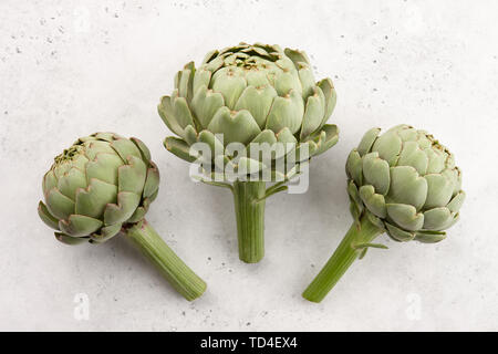 Fresh green artichokes on white stone background Stock Photo