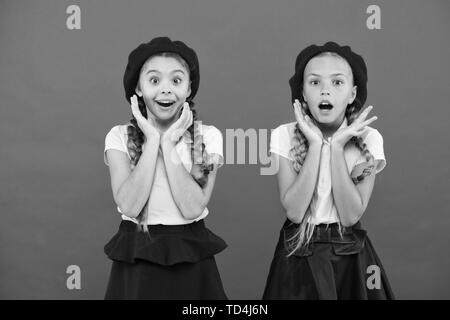 School fashion concept. Surprised girls wear formal uniform red background. International exchange school program. Education abroad. Apply form enter international school. French language school. Stock Photo