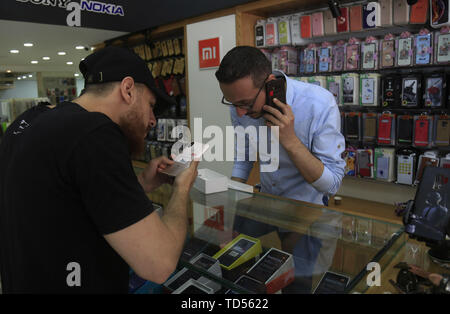 Gaza. 10th June, 2019. A customer tries a mobile phone at a store in Gaza City, June 10, 2019. Chinese-made smartphones and tablets are gaining popularity in the Gaza Strip, with praise for their advantages and affordable prices as well as local people's desire to defy U.S. sanctions. TO GO WITH Feature: Gazans buy Chinese-made phones to defy U.S. sanctions Credit: Stringer/Xinhua/Alamy Live News Stock Photo