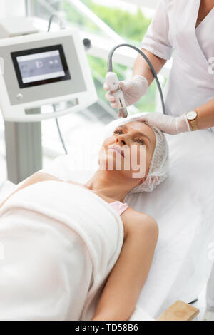 No wrinkles. Nice mature woman having a facial lifting procedure while fighting with wrinkles Stock Photo