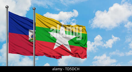 Myanmar and Haiti flag waving in the wind against white cloudy blue sky ...
