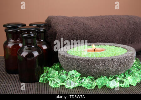 Candle in stone bowl with marine salt, on bamboo mat, on brown background Stock Photo