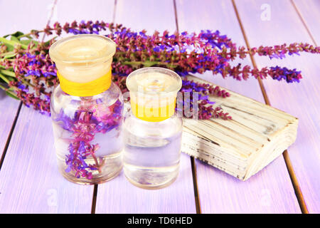 Medicine bottles with salvia flowers on purple wooden background Stock Photo