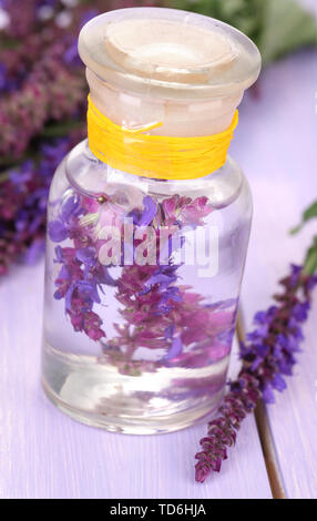 Medicine bottle with salvia flowers on purple wooden background Stock Photo