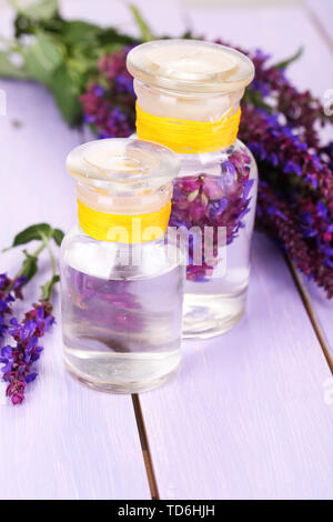 Medicine bottles with salvia flowers on purple wooden background Stock Photo