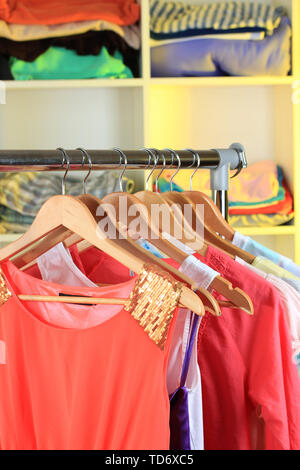 Variety of clothes on wooden hangers on shelves background Stock Photo