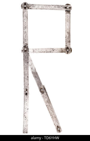 Old iron meter ruler. Old iron folding meter in the shape of letter R isolated on white background. Stock Photo