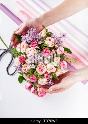 Small business concept. Work process of florist. Female hands making wedding bouquet on a white background. Stock Photo