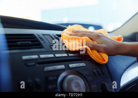 Image of male's hand with orange rag washing car interior Stock Photo