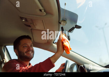 Photo of man with orange rag washing mirror car Stock Photo