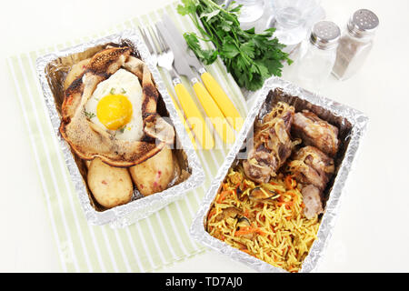 Food in boxes of foil on tablecloth Stock Photo