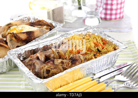 Food in boxes of foil on tablecloth Stock Photo