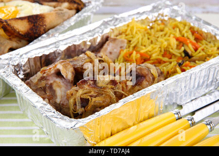 Food in boxes of foil on tablecloth Stock Photo