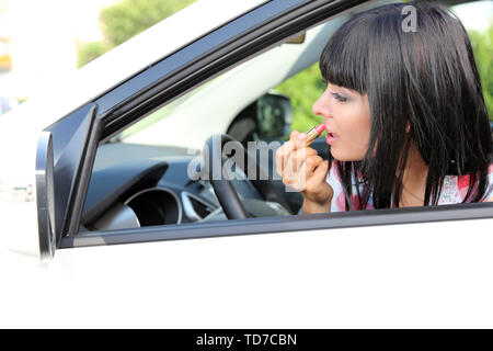 Young  woman applying makeup in car Stock Photo