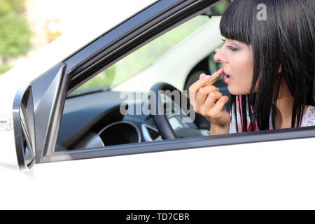 Young  woman applying makeup in car Stock Photo