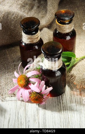 Medicine bottles with purple echinacea flowers on wooden table with burlap Stock Photo