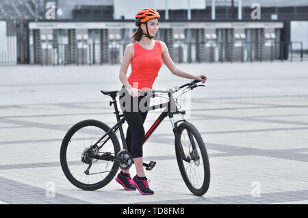 Pretty fitness girl dressed in outfit with sport bike is walking in the city Stock Photo