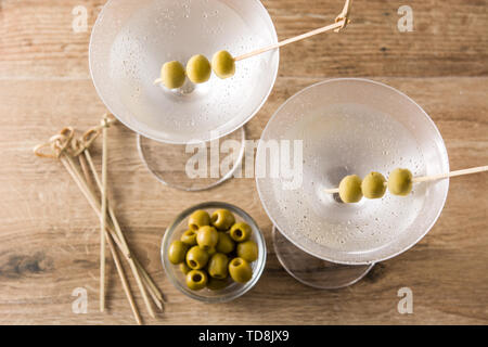 Classic Dry Martini with olives on wooden table and gray background
