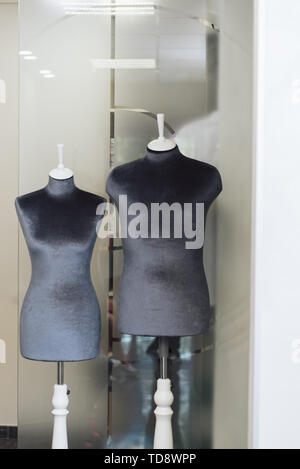 dummy in the shape of a human body in a dark color of silk black fabric. mannequin in a seamstress workshop. vertical photo. Stock Photo