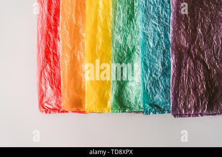 Plastic bags in a row by the colors of the rainbow on grey background. Stock Photo