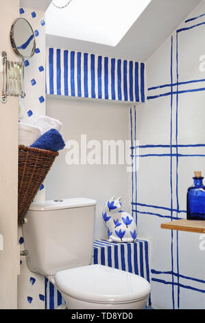 Rolled-up towels in hanging wicker basket and patterned ceramic cat next to toilet in attic bathroom  UK & IRISH USE ONLY Stock Photo