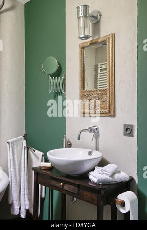 Mirror in wooden carved frame above washbasin on wooden table in bathroom   UK & IRISH USE ONLY Stock Photo