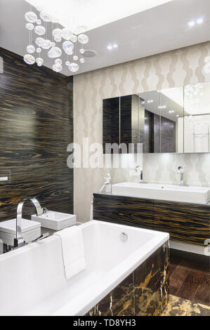 Portoro marble tiled bathtub and washbasin on ebony veneer cabinet in modern bathroom   UK & IRISH USE ONLY Stock Photo