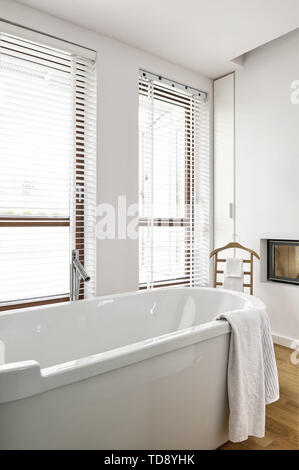 Wooden towel rack behind freestanding bathtub in minimalist bathroom   UK & IRISH USE ONLY Stock Photo