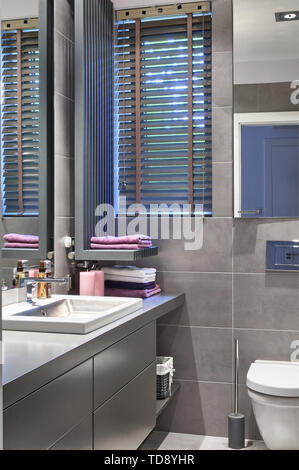 Candles and folded towels next to washbasin in gray bathroom   UK & IRISH USE ONLY Stock Photo