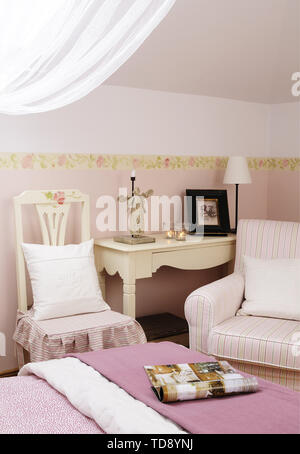 Monogrammed pillow on wooden chair next to side table in front of comfortable double bed in bedroom    UK AND IRISH RIGHTS ONLY Stock Photo