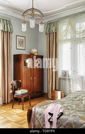 Wooden chair next to art nouveau wardrobe in retro style bedroom   UK & IRISH USE ONLY Stock Photo