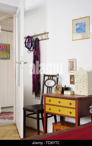 Wooden chest of drawers and vintage chair next to entrance to bedroom   UK & IRISH USE ONLY Stock Photo