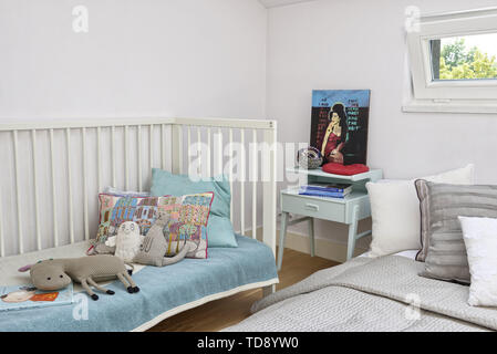 Handmade toys and pillows in baby crib standing next to floor bed   UK & IRISH USE ONLY Stock Photo