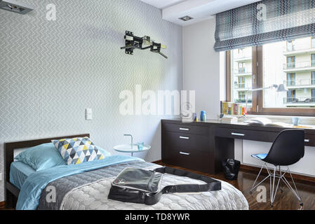 Over the shoulder handbag lying on single bed in teen boy bedroom    UK AND IRISH RIGHTS ONLY Stock Photo