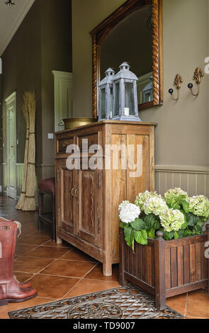 Hydrangea flowers in wooden box next to wooden cupboard in country style hallway   UK & IRISH USE ONLY Stock Photo