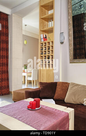 Red candles and linen table runner on coffee table standing in front of sofa with pillows in modern living room    UK AND IRISH RIGHTS ONLY Stock Photo