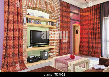 TV and audio video equipment on recessed brick wall shelves in modern living room    UK AND IRISH RIGHTS ONLY Stock Photo