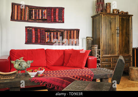 Akha tribe wall runners above red leather in ethnic style living room    UK AND IRISH RIGHTS ONLY Stock Photo