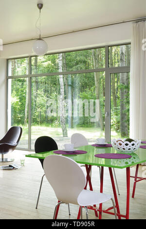 Green dining table in modern room with view to garden   UK & IRISH USE ONLY Stock Photo