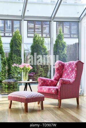 Wingback chair with pink patterned upholstery fabric in patio room   UK & IRISH USE ONLY Stock Photo